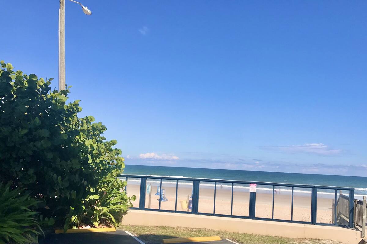 A beach view with a wooden fence, a lifeguard tower, and a clear blue sky.