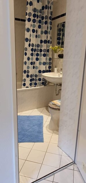 A bathroom with a white sink, a toilet, and a shower curtain with a blue and white polka dot pattern.