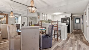 Eine moderne Küche mit weißen Schränken, einem Edelstahlkühlschrank und einem Essbereich mit rundem Tisch und Stühlen.