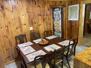 A wooden-paneled dining room with a table set for four, featuring placemats and a wooden centerpiece.