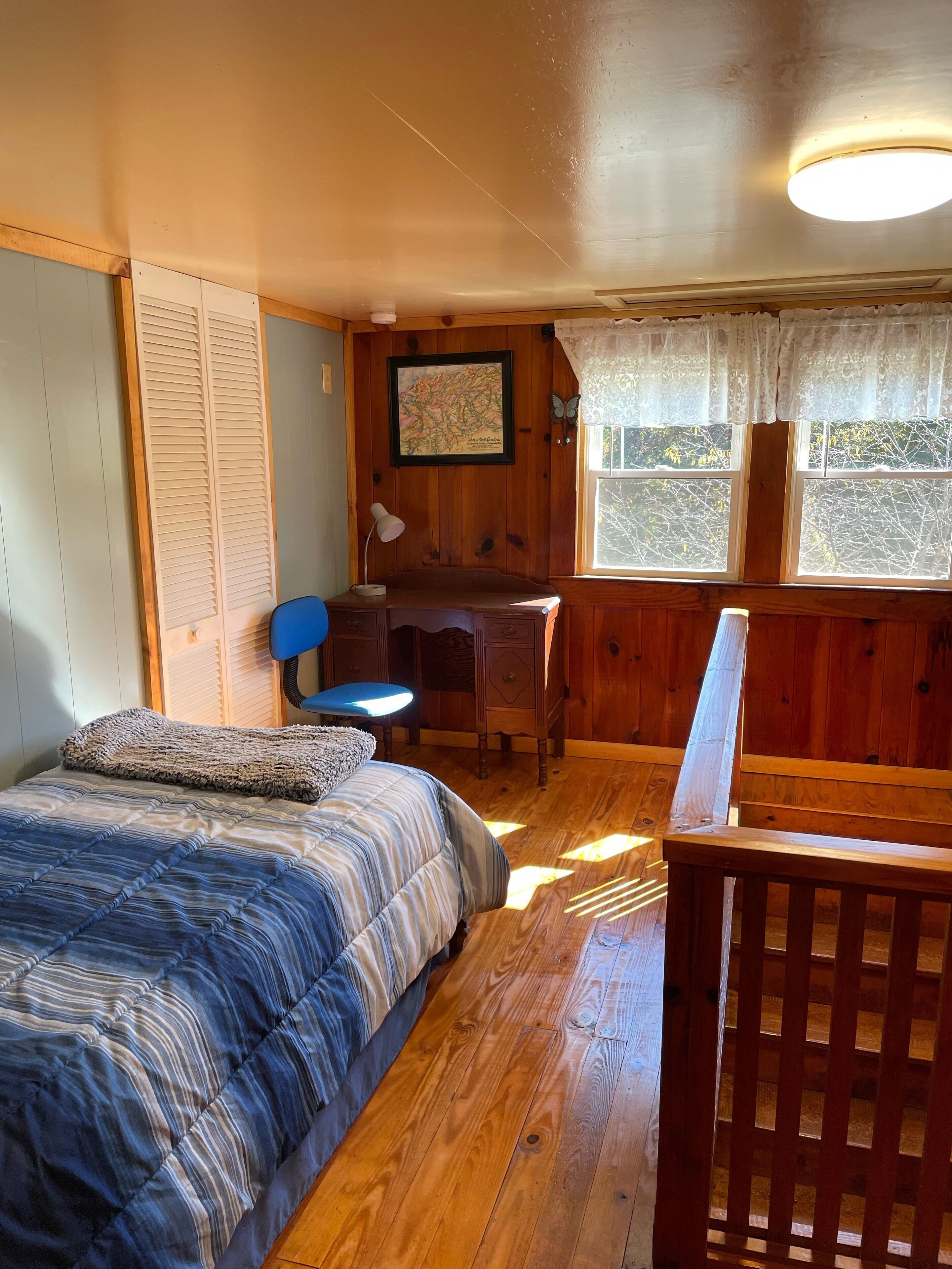 A cozy room with a bed, desk, and window.