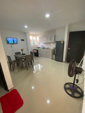 A modern kitchen with white cabinets, a dining area with a table and chairs, and a red rug. - APARTMENT 204 5 MIN FROM THE HISTORICAL CENTER (Cartagena de Indias)