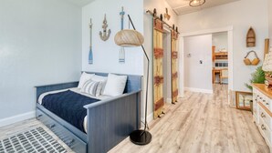 Ein Schlafzimmer mit einem Bett, einer Nachttischlampe und Wandbildern mit Seefahrer-Motiven.
