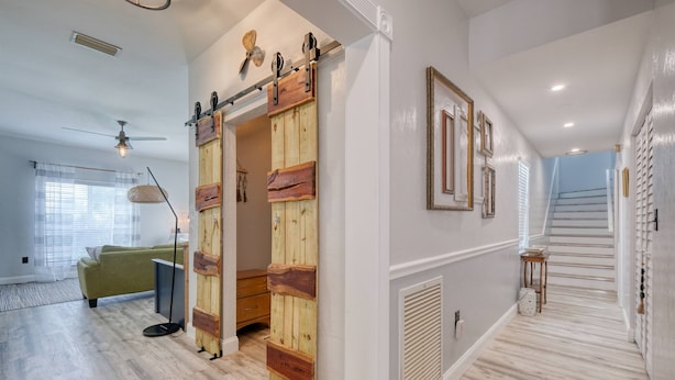 Ein modernes Interieur mit einer Holztür zum Verschieben, einer Treppe und einem grünen Sofa.