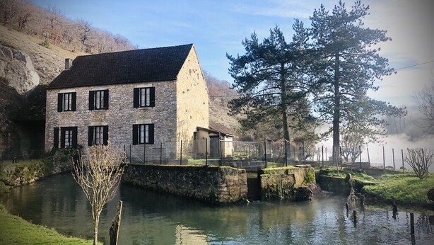 A stone building with a sloped roof, a small adjacent structure, and a river with a lock system. - Gîtes Onyx: l'Albizia, Lot - Vallée de la Dordogne (Bétaille)