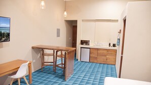 A compact kitchen with a wooden table and chairs, a microwave, and a sink.