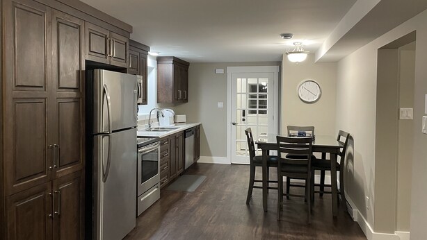 Una cocina moderna con gabinetes de madera oscura, electrodomésticos de acero inoxidable y un comedor con mesa y sillas.