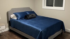 Un dormitorio con cama, ventana y mesita de noche.