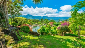 A lush garden with a pond, palm trees, and a view of distant mountains. - (4323) 1 Br Hanalei Bay Resort, Ocean view and Plenty of Amenities (Princeville)