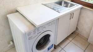 Ein kleiner Waschbereich mit Waschmaschine, Spüle und Fenster.