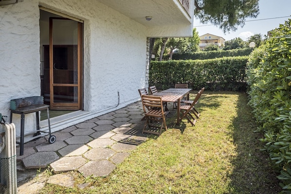 A patio with a table and chairs, a sliding glass door, and a stone pathway leading to a house.