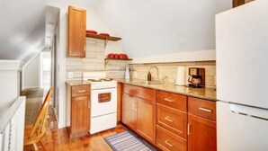Una cocina compacta con armarios de madera, una estufa blanca y una encimera con cafetera.