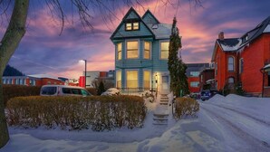 Una casa de dos pisos con techo inclinado y porche delantero, rodeada de nieve.