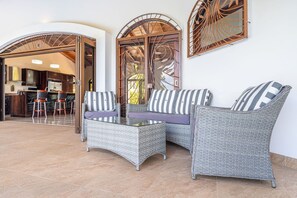 A patio area with wicker furniture, including a sofa and chairs, and a glass-top table. - Casa Blanca Ocean View 3 Suites (Ojochal)