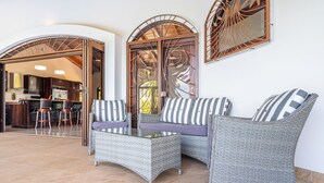 A corner seating area with wicker furniture, a glass-top coffee table, and striped cushions. - Ocean-View Villa · Whale Season · 20 min to Marino Ballena. (Ojochal)