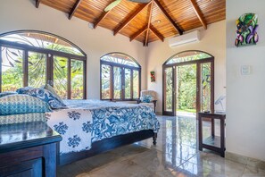 A bedroom with a large bed, multiple windows, and a wooden ceiling. - Casa Blanca Ocean View 3 Suites (Ojochal)
