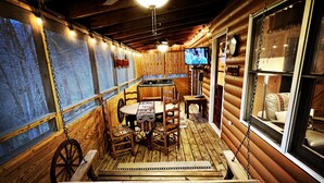 L’intérieur d’un chalet accueillant, avec une table à manger en bois, des chaises, un banc et un téléviseur fixé au mur.