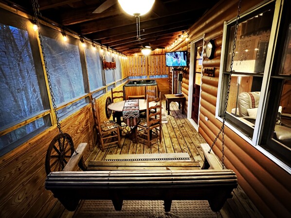 A cozy cabin interior with a wooden dining table, chairs, a bench, and a television mounted on the wall.