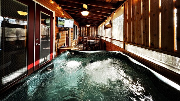L’intérieur d’un chalet en bois, avec un jacuzzi, des murs en bois et un téléviseur diffusant l’émission « FARMERS ».