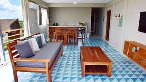 A room with a sofa, dining table, and chairs, a kitchen area, and a balcony with a view. - Beachfront 1BR Apartment w/ Terrace & Beach Club (Mahahual)