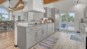 Une cuisine spacieuse avec des meubles de couleur grise, un grand îlot central et une vue sur un patio.