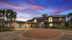 Une maison à deux étages avec une allée, un garage et une terrasse circulaire en briques.