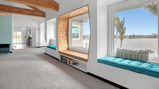 Un intérieur moderne avec un banc intégré placé près d’une grande fenêtre donnant sur un plan d’eau.