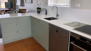 A modern kitchen with a dishwasher, a sink, and a window with blinds.