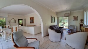 A spacious living area with a modern design, featuring a large arched doorway, multiple seating options including a sofa and chairs, and a dining area with a table and chairs. - Attractive family home for 10 people in popular Hossegor lake district (SOORTS HOSSEGOR)