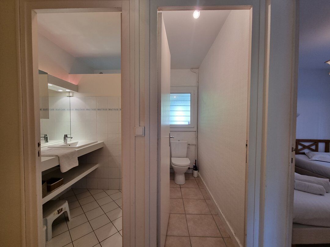 Un baño con inodoro, lavamanos y estantes.