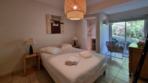 A bedroom with a bed, bedside lamps, a hanging light fixture, a chair, and a view of the outdoors. - Attractive family home for 10 people in popular Hossegor lake district (SOORTS HOSSEGOR)