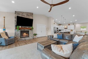 A spacious living room with a fireplace, leather sofas, and a flat-screen TV. - Unique Lakeview Home with Indoor Pool in Basement! (Branson)