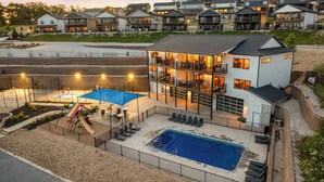 A multi-story residential building with a pool, outdoor seating, and a basketball court.