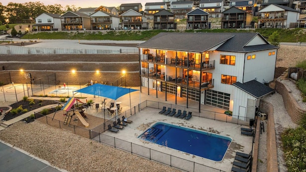 A multi-story residential building with a pool, outdoor seating, and a basketball court. - Unique Lakeview Home with Indoor Pool in Basement! (Branson)