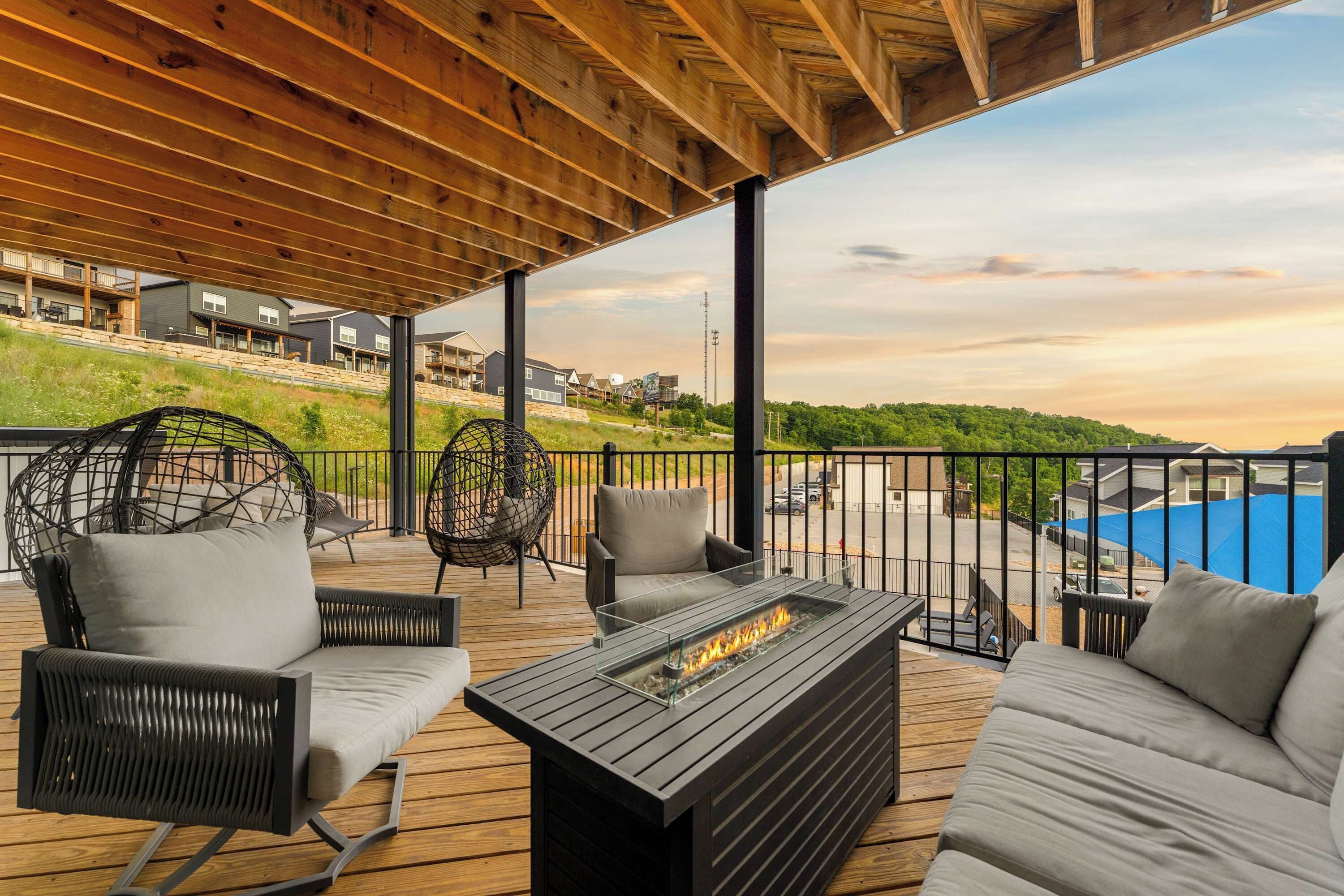 Une terrasse extérieure couverte, aménagée avec des sièges, un foyer et offrant une vue sur un quartier résidentiel.