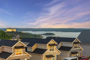 A residential area with multiple houses, a large building in the distance, and a body of water. - Unique Lakeview Home with Indoor Pool in Basement! (Branson)