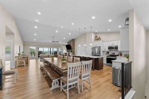 A spacious kitchen with modern appliances, a dining area with wooden furniture, and large windows offering a view. - Unique Lakeview Home with Indoor Pool in Basement! (Branson)