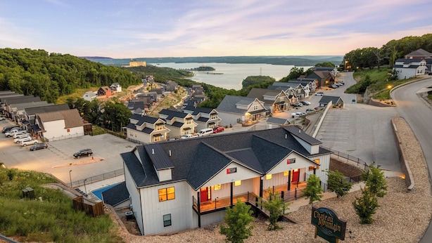 A hotel with a swimming pool, a parking lot, and a view of a lake.