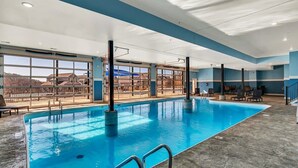 An indoor swimming pool with clear views through large windows, a concrete floor, and a blue and white color scheme. - Unique Lakeview Home with Indoor Pool in Basement! (Branson)