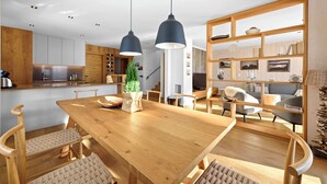 Una cocina moderna con armarios de madera, un comedor con mesa y sillas de madera, e iluminación colgante.
