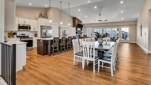A spacious kitchen with modern appliances, a dining area with white chairs, and a large window offering a view. - Lake View! Indoor and Outdoor Pool! (Branson)