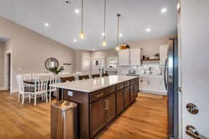 A modern kitchen with a central island, white cabinetry, and pendant lighting. - Lake View! Indoor and Outdoor Pool! (Branson)