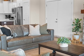 A modern living room with a leather sofa, a coffee table, and a potted plant.