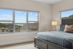 A bedroom with a large window, a bed with a headboard, a nightstand, and a lamp. - Lake View! Indoor and Outdoor Pool! (Branson)