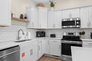 Eine moderne Küche mit weißen Schränken, Edelstahlgeräten und einem eingebauten Backofen.