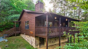 A rustic cabin with a stone foundation, wooden exterior, and a covered porch.