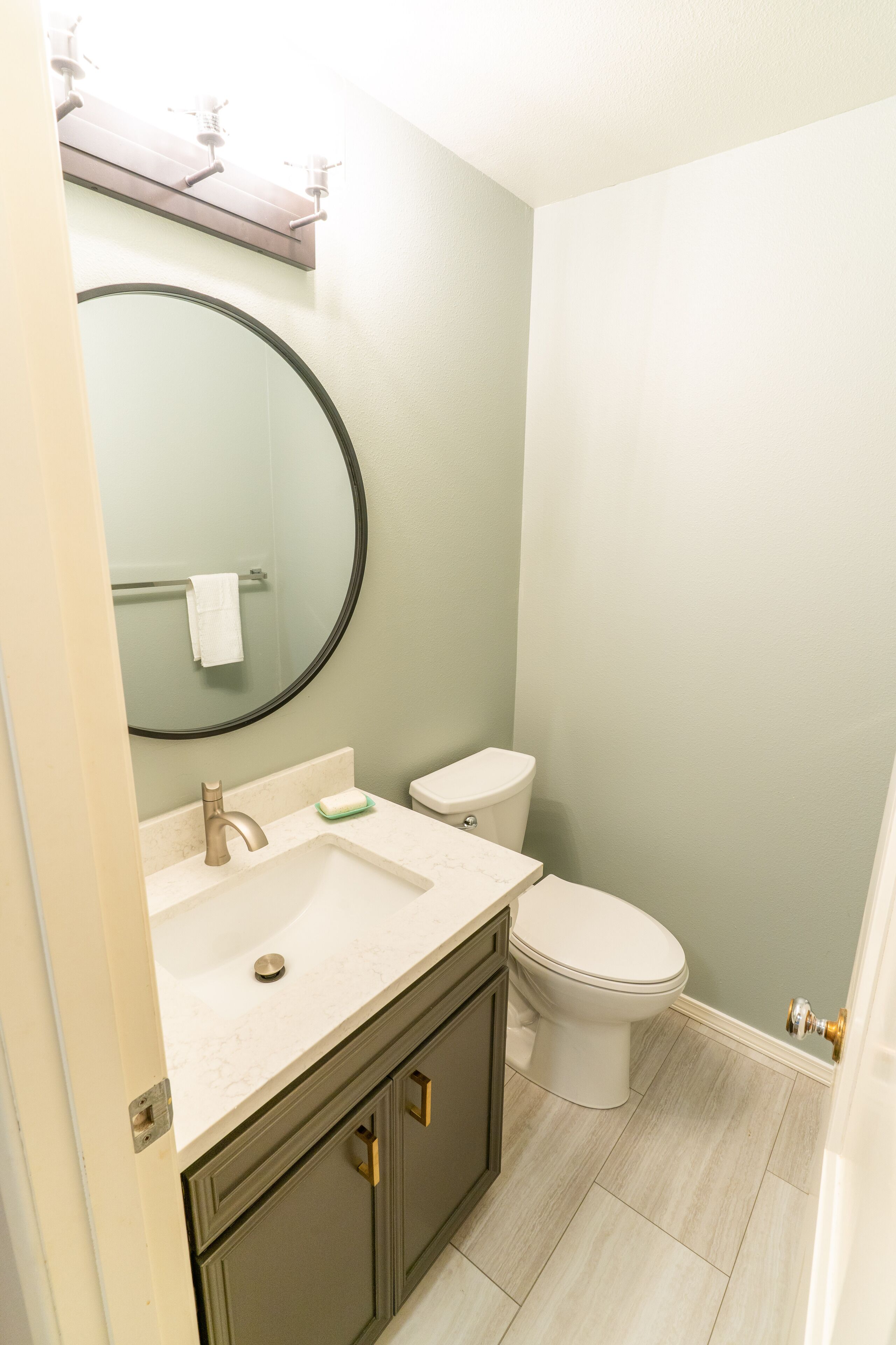 A bathroom with a sink, mirror, toilet, and a towel rack.