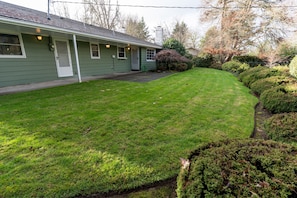 A green house with a well-maintained lawn and a small garden area.
