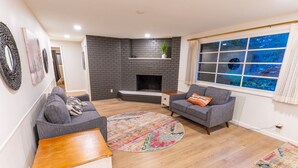 Una sala de estar con chimenea, dos sofás, una mesa de centro y un ventanal con vistas.