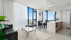 Ein modernes Wohnzimmer mit einer Couch, einem Couchtisch und Blick auf die Stadt durch große Fenster.